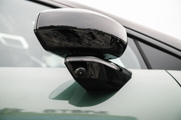 Camera 360 on a mirror on green new modern electric sedan car closeup. Road safety. 360 terrain...