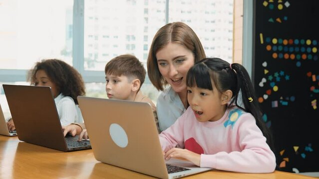 Smart teacher teaching and looking student using laptop at classroom. Professional instructor explained about programing engineering code or prompt while studying and learning program. Erudition.