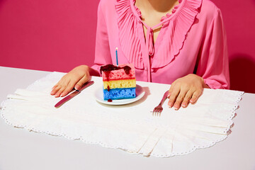Cropped image of woman in pink shirt sitting at table with plate and birthday cake made of dishwashing sponges and candle. Birthday. Concept of food pop art photography, creativity, weirdness,