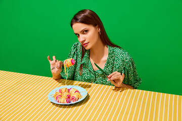 Young woman eating spaghetti on hair curlers against green background. Unusual presentation of food. Modern menu. Concept of food pop art photography, creativity, quirky style