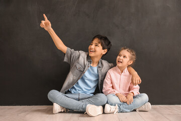 Little children pointing at something near blackboard