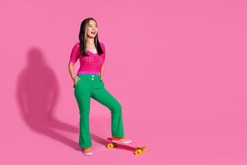 Fototapeta na wymiar Full length photo of funky impressed lady dressed knitted shirt riding skate board looking empty space isolated pink color background
