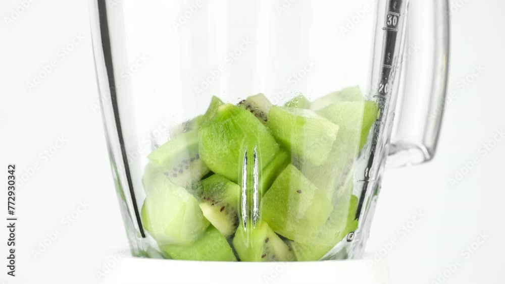 Wall mural add chopped kiwi fruit in blender, white background