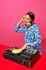 Young stylish woman, dj using sound mixer with pancake instead of vinyl record on pink background....