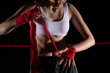 The athlete wraps her hands with a boxing bandage. Preparation for an important fight. The woman focused during the last steps before going to the ring.