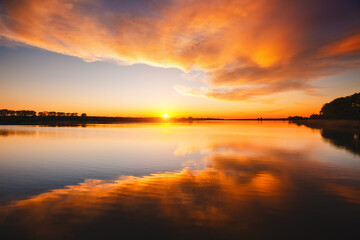 Attractive view of the sunset over the calm surface of the water. - 772931956