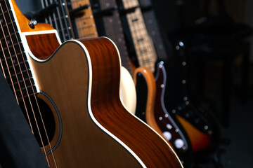 Close-up of beautiful guitars standing in a row near the wall in a music studio or in a store,...