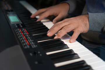 Close-up of male hands playing an electronic piano. Musical education at a music school. Private music lessons with a teacher.