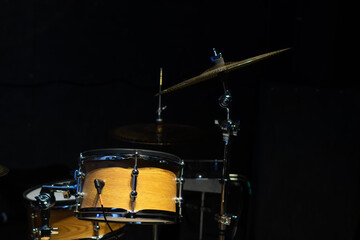 Close-up of a fragment of a drum kit matching the color of a tree in the studio on a black background