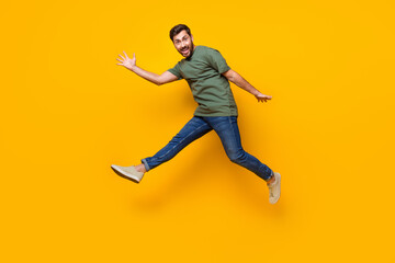 Full length photo of nice young male jump running fast dressed stylish khaki garment isolated on yellow color background