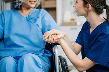 Nurse helping elderly woman walk in the room, holding his hand, supporting. Treatment and...