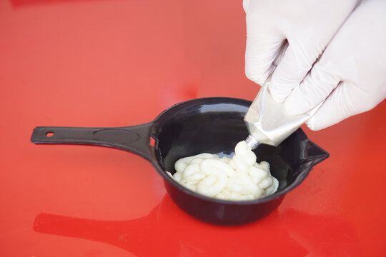 Close up hands wears gloves, squeezes dye hair color cream from tube in mix in black bowl before dying client's hair. Concept, hair beauty product for changing hair color by professional hairdresser. - Powered by Adobe