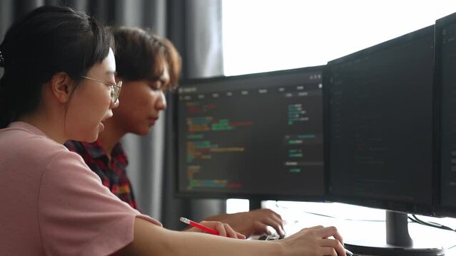 Slow motion back end software developer engineer for computer programming working together on debugging writing computing code, solving complex algorithms display on monitor in office. Burgeoning