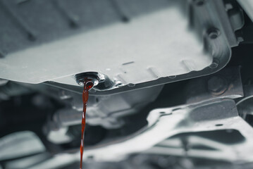 Close-up view of motor oil being drained from a car during a routine oil change service..