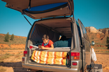 Young boy chatting with smartphone in the van in the red canyon of Teruel, Spain.