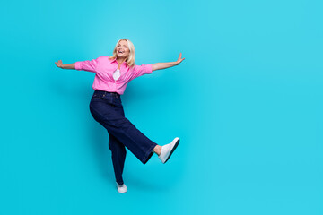 Full size photo of pretty pensioner lady dance spread arms dressed stylish pink smart casual outfit isolated on aquamarine color background