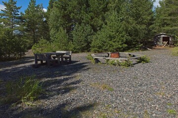 Public fire place and wooden bench and table on the island of Jussarö in summer, Raasepori, Finland.