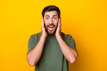 Photo of funny excited man wear khaki t-shirt open mouth arms cheeks isolated yellow color...