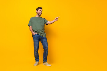 Full size photo of handsome young guy point look empty space dressed stylish khaki outfit isolated on yellow color background