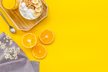 food for healthy breakfast with granola and fresh orange juice on bright yellow background top view mock up