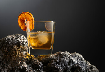 Old fashioned cocktail with ice and dried orange slice.