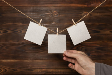 man hand take paper note cards hanging with wooden clip or clothespin on rope string peg on wooden...