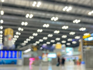 blurred photography of the terminal hall at the airport where travellers walk and bokeh of light bulbs on the ceiling