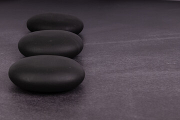Smooth round hot stone massage stones on grey background. Spa therapy. Hot stone massage. 