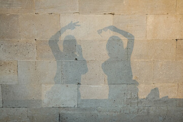 A shadow on a stone wall from the silhouettes of two girls.