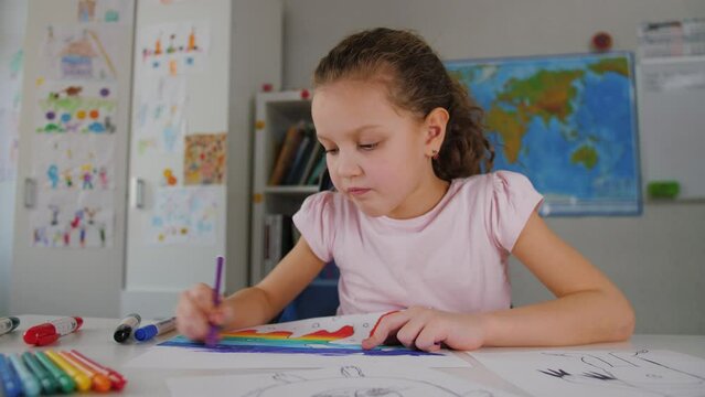 Little kid girl study at home, drawing picture by felt-tip markers pens, playing alone. Cute concentrated preschool child coloring picture, enjoy creative activity, children playtime education