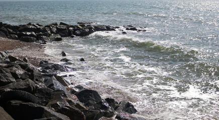 Fototapeta premium Rocky coast with sparkling waves crashing on the shore