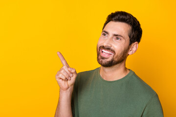 Photo of attractive dreamy man wear khaki t-shirt pointing finger looking empty space isolated...