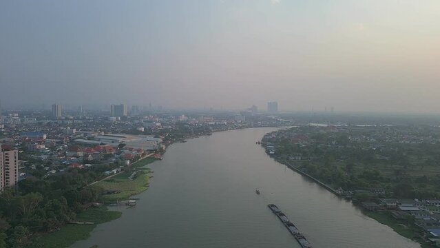 A panoramic cityscape featuring a vibrant river winding through the urban landscape, with ships dotting the harbor and a vibrant sunset sky in bangkok ,view bird eye view by drone