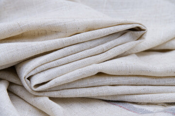 Folded cream-colored calico fabric texture. Close-up bright cream canvas for fibers and textiles....