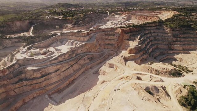 This image captures the vastness of a working limestone quarry from a bird's-eye view, highlighting the layered excavations and machinery at work.