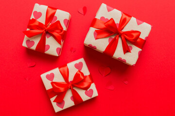 Top view photo of valentine day decorations gift box with red ribbon bow on colored background. Holiday gift boxes with top view