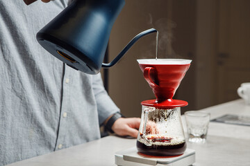 Pouring Hot Water From Kettle Into Red Coffee Funnel Over Glass Carafe On Scale Close-up