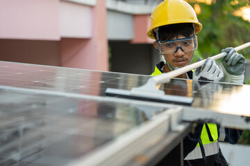 Asian male worker uses a rubber sheet and water to clean the solar panels on the roof of house....