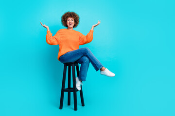 Full body photo of friendly cheerful lady sit chair raise hands communicate empty space isolated on teal color background