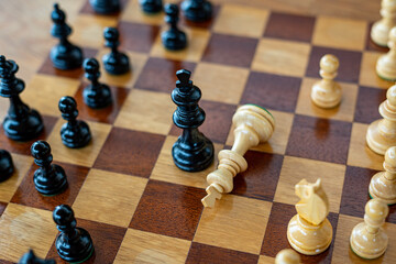 Black chess king defeated white king on wooden chess board