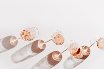Set of glasses of rose wine at wine tasting, Minimal trend concept. Top view crystal wineglass standing at sunlight, shadow and sun glare, beige pink colored, alcohol drink background, copyspace - obrazy, fototapety, plakaty