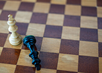Defeated black chess king white victory king on wooden chess board with right space
