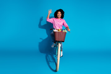 Full length photo of cheerful pleasant girl dressed silk shirt jeans riding bike waving palm say hi...