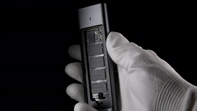 Hand Grasping Open SSD Case with inside M.2, External USB Drive on black. High quality photo