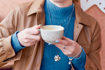 Woman with blue manicure holds a coffee cup close up