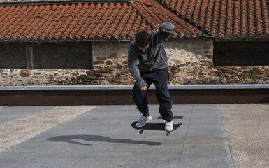 Skater captured in mid-air trick against rustic background, copy space. - obrazy, fototapety, plakaty
