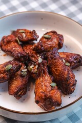 Buffalo wings sprinkled with nuts on a checkered tablecloth