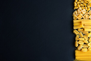 Italian Pasta variations on Black graphite board background, top view. Italian dry Pasta variation...