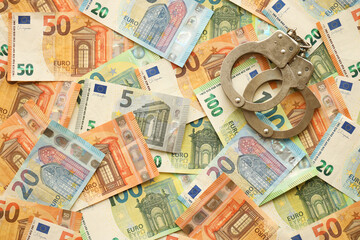 Many European euro money bills and handcuffs. Lot of banknotes of European union currency and cuffs close up
