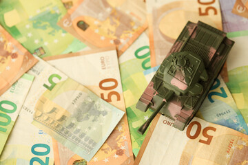 Many euro banknotes and tank. Lot of bills of European union currency and green tank close up